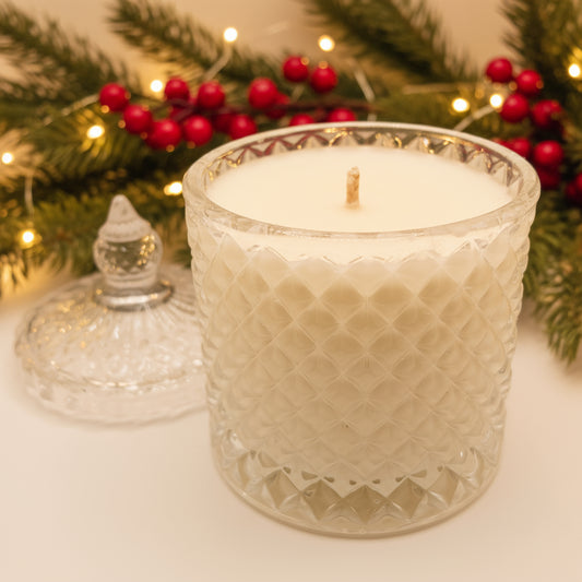 White candle in a decorative glass holder with blurred lights in the background